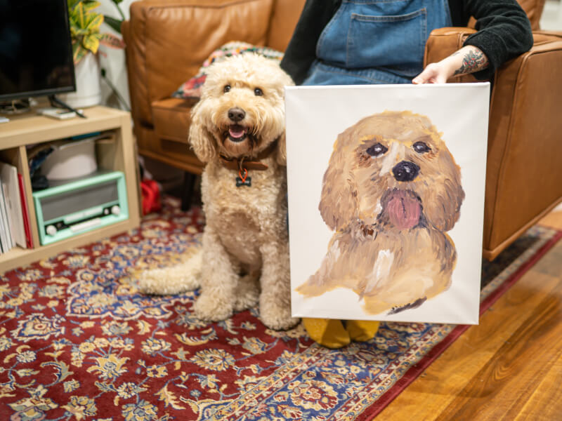 Dog posing with their portrait from a painting class